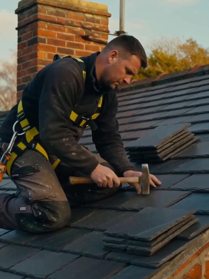 A roofer laying slate tiles